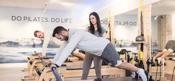Pilates Teilnehmer mit Trainerin
